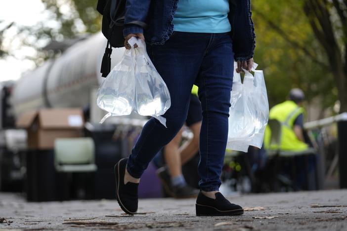 A person carries bags of fresh water after filling up from a tanker at a distribution site in the aftermath of Hurricane Helene on Wednesday in Asheville, N.C.