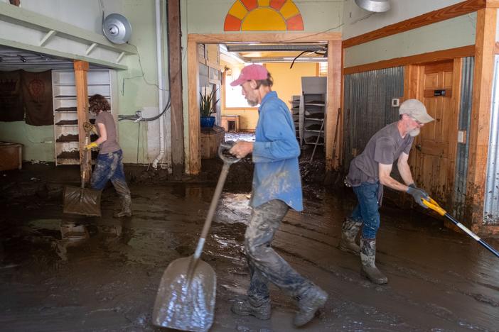 Residents work hard to shovel the mud out of the town's natural grocery store. French Broad River, which runs through the town of Marshall, crested over 24 feet during Hurricane Helene. The river level has gone down, but left behind knee-deep sediment inside the buildings.