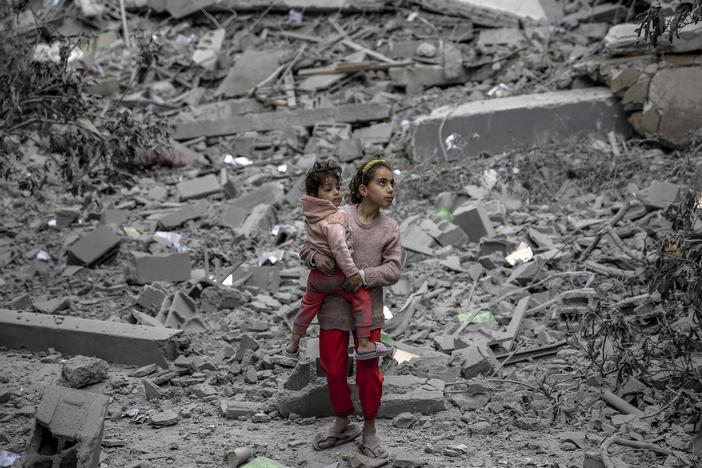 A Palestinian girl carries a child through the rubble of houses destroyed by Israeli bombardment in Gaza City on March 3, amid the ongoing conflict between Israel and the Hamas movement.