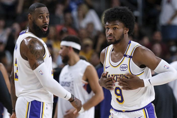 Los Angeles Lakers guard Bronny James (9), right, steps onto the court with Los Angeles Lakers forward LeBron James (23) during the first half of a preseason NBA basketball game Sunday in Palm Desert, Calif.