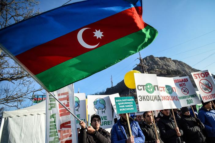 An Azerbaijani environmental activist waves a national flag during a protest against what they claim is illegal mining at the Lachin corridor, the only land link between the Armenian-populated breakaway Nagorno-Karabakh region and Armenia.