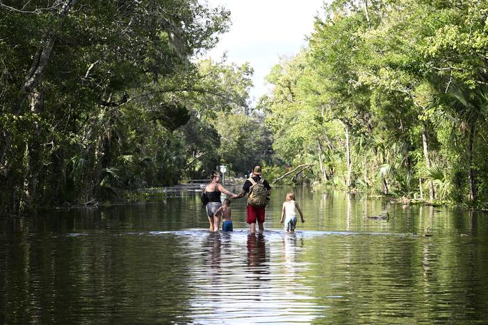 Dustin Holmes, second from right, holds hands with his girlfriend, Hailey Morgan, while returning to their flooded home with her children Aria Skye Hall, 7, right, and Kyle Ross, 4, in the aftermath of Hurricane Helene, Friday, Sept. 27, 2024, in Crystal River, Fla.