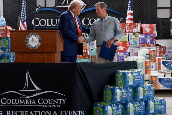 Republican presidential nominee, former President Donald Trump, and Georgia Gov. Brian Kemp shake hands as they visit the area while it recovers from Hurricane Helene on Oct. 04 in Evans, Ga.