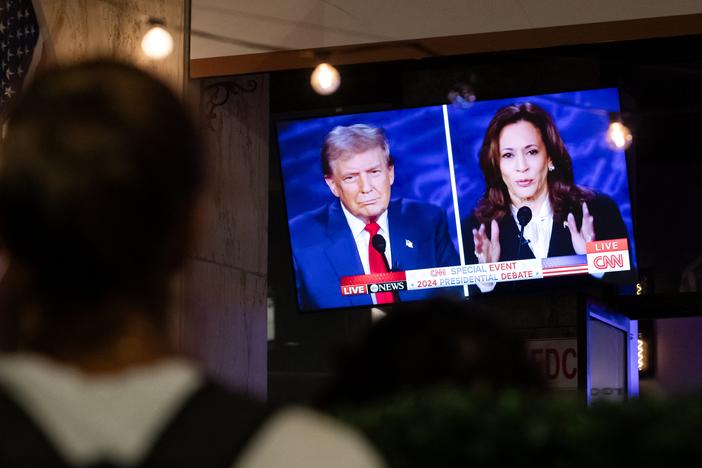 A person stops to watch a screen in Washington, D.C., displaying the presidential debate between Vice President Harris and former President Donald Trump in September.