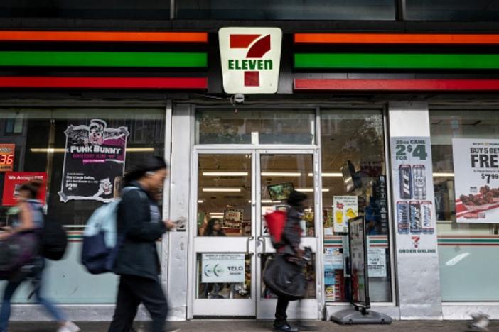 People walk past a 7-Eleven convenience store in New York City on Wednesday. The company plans to shut down 444 stores across North America to recoup costs lost to inflation, a drop in store traffic and declining cigarette sales.