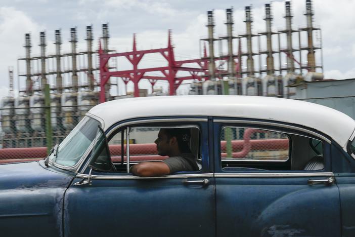 A person drives a classic American car past a floating generator that has not been producing electricity for days in Havana, Cuba, Friday, Oct. 18, 2024.