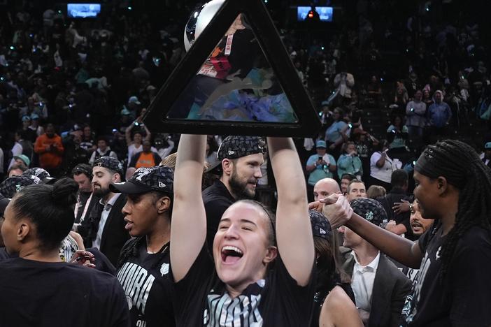 New York Liberty guard Sabrina Ionescu holds up the championship trophy after the Liberty defeated the Minnesota Lynx in Game 5 of the WNBA basketball final series, Sunday, Oct. 20, 2024, in New York.