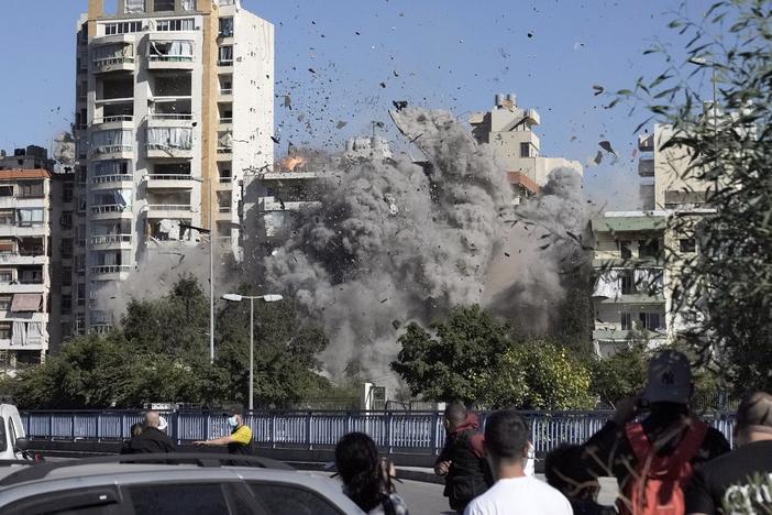 People watch a building collapse after being hit by an Israeli airstrike in Ghobeiri, Beirut, Lebanon, on Tuesday.
