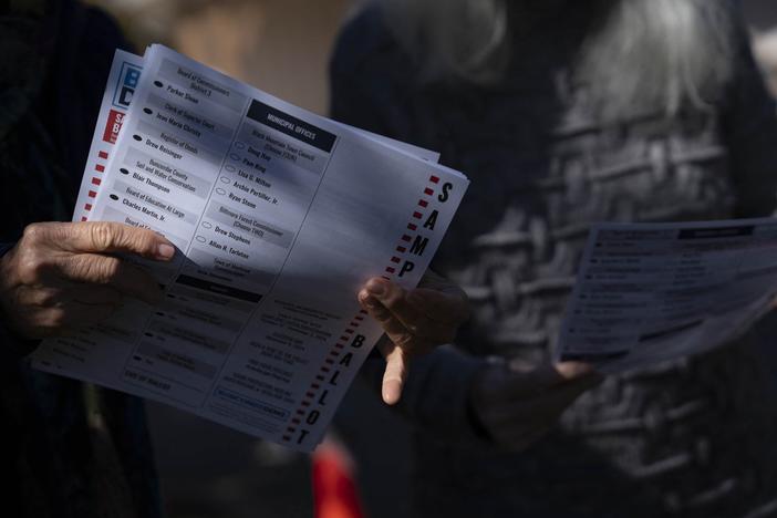 A woman holds a sample ballot on the second day of early voting at a polling station, Oct. 18, in Fairview, North Carolina. Despite concerns about early voting access after Hurricane Helene, many local officials reported record turnout for early voting, like in nearby Yancey County.