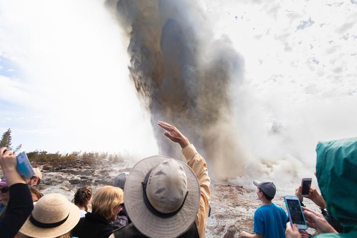 Wyoming, USA - A crowd of people witness the rare eruption of Steamboat Geyser, the largest active geyser in the world.