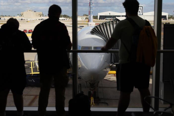 Passengers look out at an American Airlines jet. The airline is cracking down on "gate lice" — passengers who crowd around departure gates in terminals, and try to jump ahead in the boarding queue.