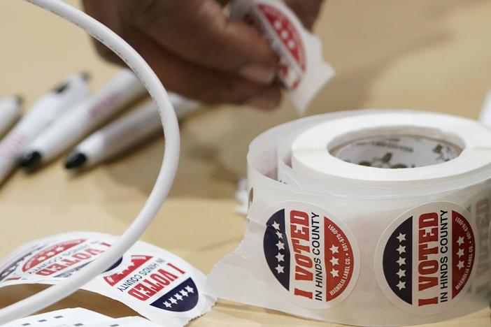 A Jackson, Miss., precinct worker reaches for more "I Voted" sticker on Nov. 7, 2023.