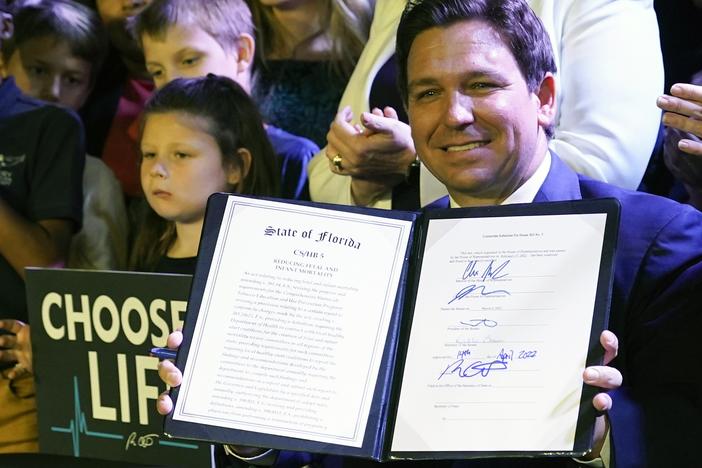 Florida Gov. Ron DeSantis holds up a 15-week abortion ban law after signing it on April 14, 2022, in Kissimmee, Fla.