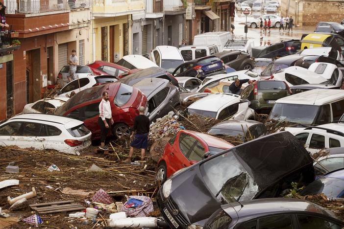 Residents look at cars piled up after being swept away by floods in Valencia, Spain, Wednesday.