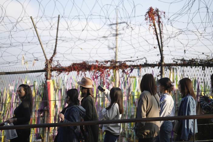 Visitors walk near a wire fence decorated with ribbons written with messages wishing for the reunification of the two Koreas at the Imjingak Pavilion in Paju, South Korea on Thursday.