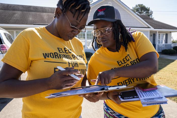 Andrea Farmer (left) and Alex Cook mark off homes they have visited on their app while canvassing in a neighborhood in Nashville, North Carolina in October.
