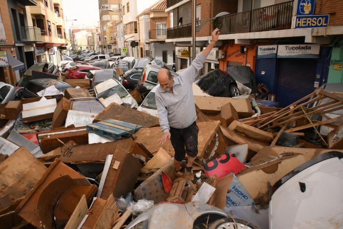 A man walks through a debris-covered street after flash floods hit eastern Spain on October 30, 2024. Climate scientists say global warming makes extreme rain events like it more likely.