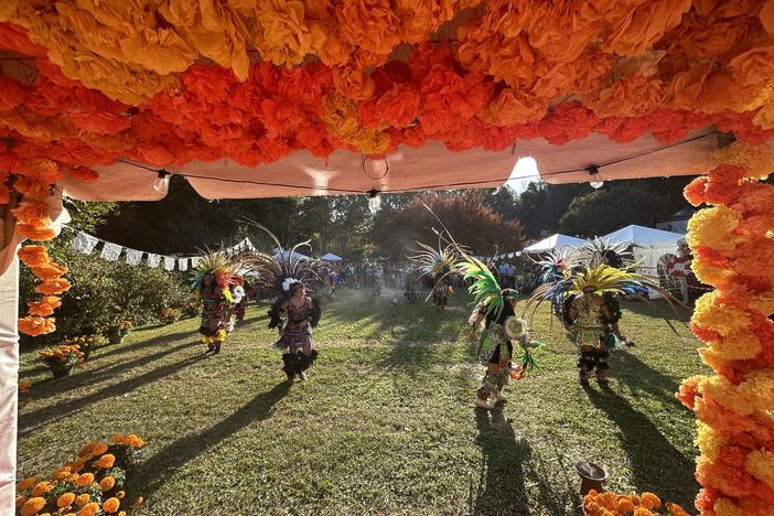 Aztec dancers circle the grounds at the Historic Oakwood Cemetery in Raleigh, North Carolina in front of Day of the Dead ofrendas.