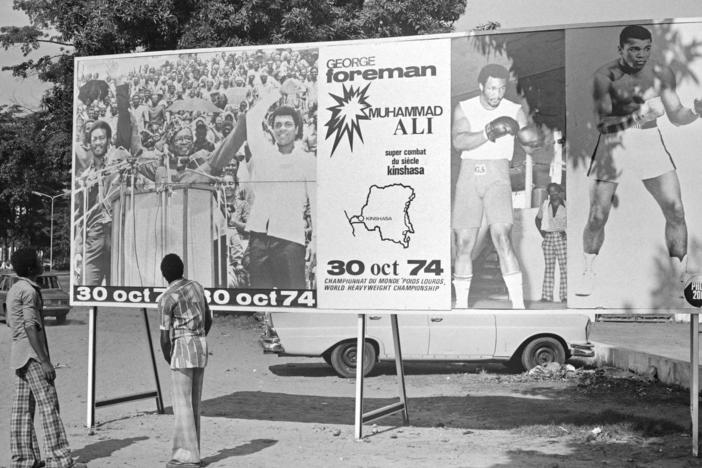People look at a billboard in Kinshasa on Oct. 30, 1974, announcing the fight between U.S. boxers Muhammad Ali and George Foreman. That day, Ali knocked out Foreman in a clash of titans known as the "Rumble in the Jungle," watched by 60,000 people in the stadium in Kinshasa and millions elsewhere.