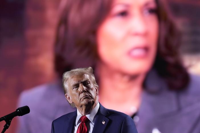 Republican presidential nominee and former President Donald Trump watches as a video featuring Vice President Harris, the Democratic presidential nominee, plays during a campaign event on Oct. 18 in Detroit.