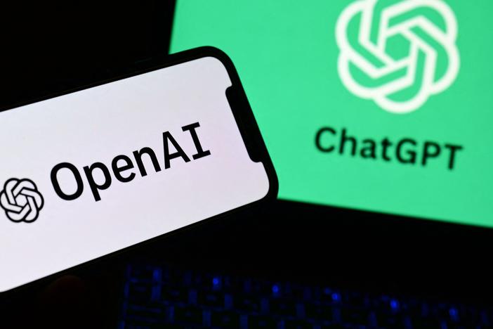 A photo taken on October 4, 2023 in Manta, near Turin,  shows a smartphone and a laptop displaying the logos of the artificial intelligence OpenAI research laboratory and ChatGPT robot.