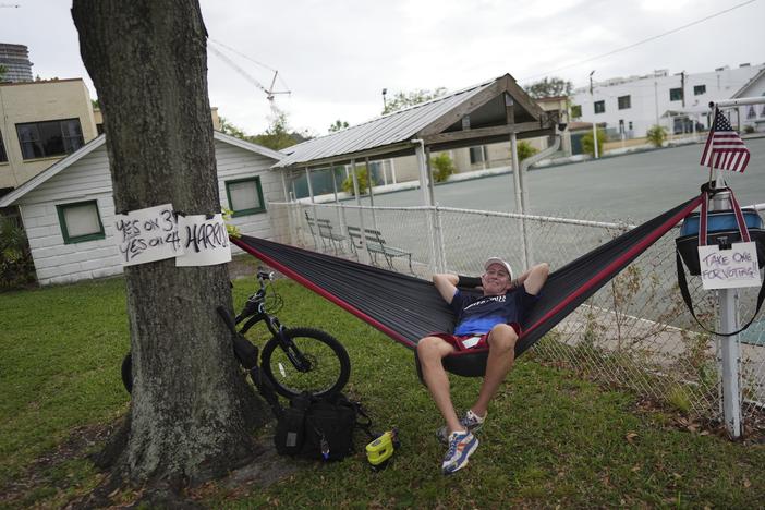 Christopher Reid, 54, a U.S. Army veteran, relaxes in a hammock alongside homemade signs supporting Democratic presidential nominee Vice President Kamala Harris and Florida's Amendments 3 and 4, which would legalize recreational marijuana and enshrine abortion rights in the state, respectively, across from a polling place at the Coliseum in downtown St. Petersburg, Florida on Tuesday.