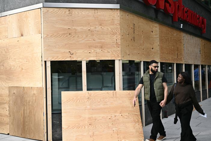 People walk past a boarded-up store in downtown Washington, D.C., on Monday. Some areas are preparing for possible election-related violence.