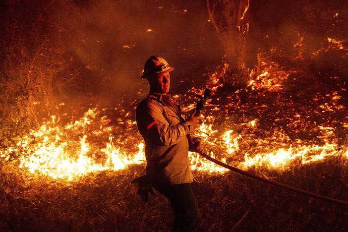 A firefighter prepares to douse flames while battling the Mountain Fire on Wednesday, Nov. 6, 2024, in Santa Paula, Calif.