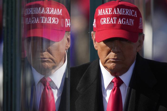 Former President Donald Trump is reflected in the bullet proof glass as he finishes speaking at a campaign rally in Lititz, Pa., on Nov. 3.
