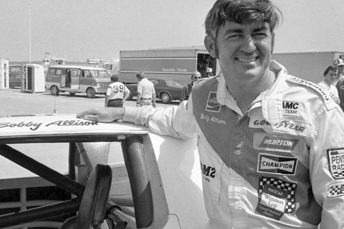 Bobby Allison stands beside his car and talks with the press after winning the pole position during qualifying for the 500 mile grand national stock car race at Pocono Raceway, Aug. 2, 1975, in Long Pond, Pa.