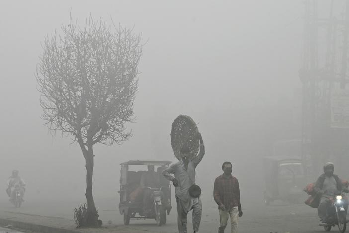 Pedestrians walk along a road engulfed in thick smog in Lahore, Pakistan, on Nov. 11. Lahore, a city of 14 million people and stuffed with factories, regularly ranks among the world's most polluted cities. It's hit record levels this month.