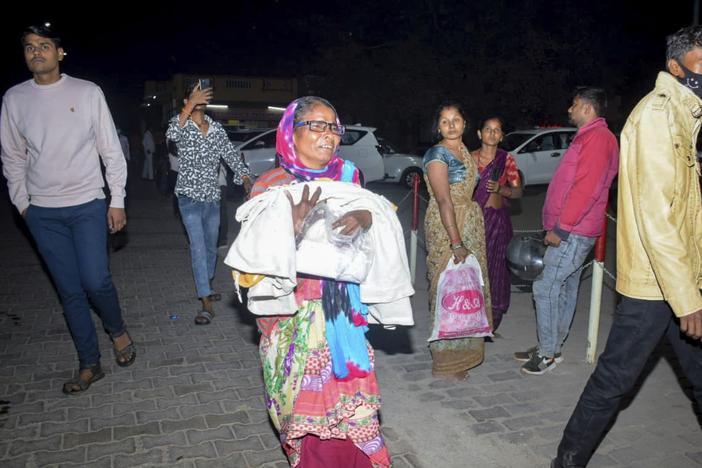 A woman rushes a child to the emergency ward after a fire broke out in a neonatal intensive care unit at Jhansi Medical College hospital in Jhansi, India, on Friday.