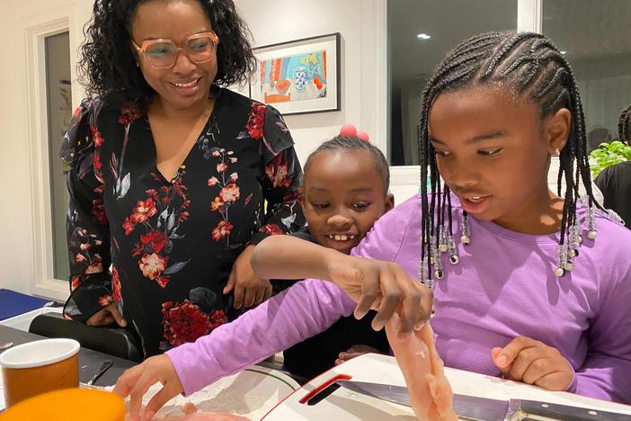 Ayesha Rascoe watches her daughters Annalise, 7, and Gabrielle, 8, prepare chicken. (left to right)