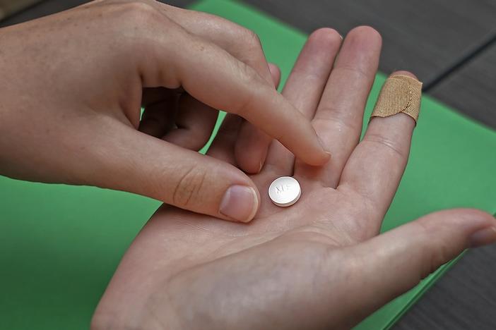 A patient prepares to take the first of two combination pills, mifepristone, for a medication abortion during a visit to a clinic in Kansas City, Kan. in 2022.