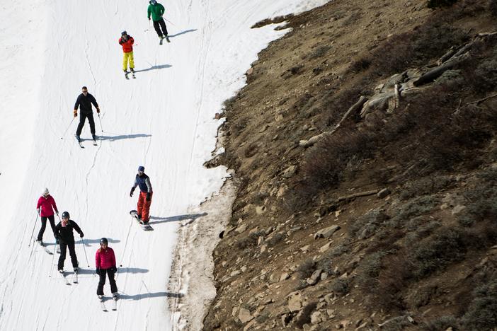 Skiers ski past dry ground at a ski resort in 2015 in Olympic Valley, Calif. The resort changed its name in 2021 and has been among the places removing a derogatory word from their names.