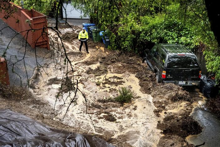 Permit Sonoma Director Tennis Wick crosses a mudslide to inspect a home as heavy rains fall near Healdsburg in unincorporated Sonoma County, Calif., on Friday.
