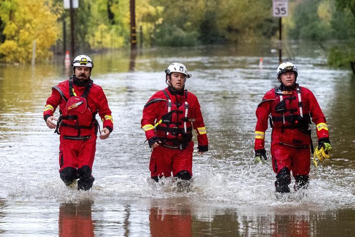 Firefighters walk through floodwaters while responding to a rescue call in unincorporated Sonoma County, Calif., on Friday, Nov. 22, 2024.