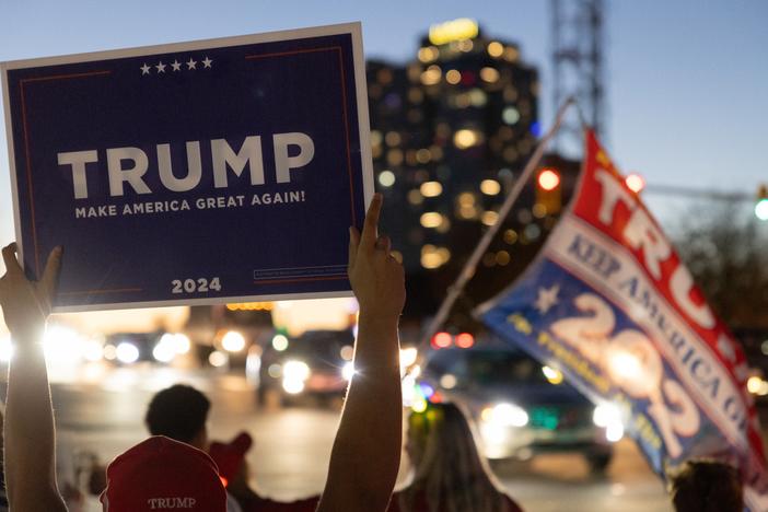 Supporters of Donald Trump, carrying flags and signs, march through a crosswalk in Virginia on Nov. 8, expressing their excitement after his 2024 presidential election win.