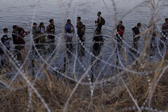 Migrants wait to climb over concertina wire after they crossed the Rio Grande and entered the U.S. from Mexico, Sept. 23, 2023, in Eagle Pass, Texas.