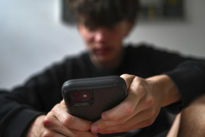 A teenager uses his mobile phone to access social media in Sydney on Nov. 13.