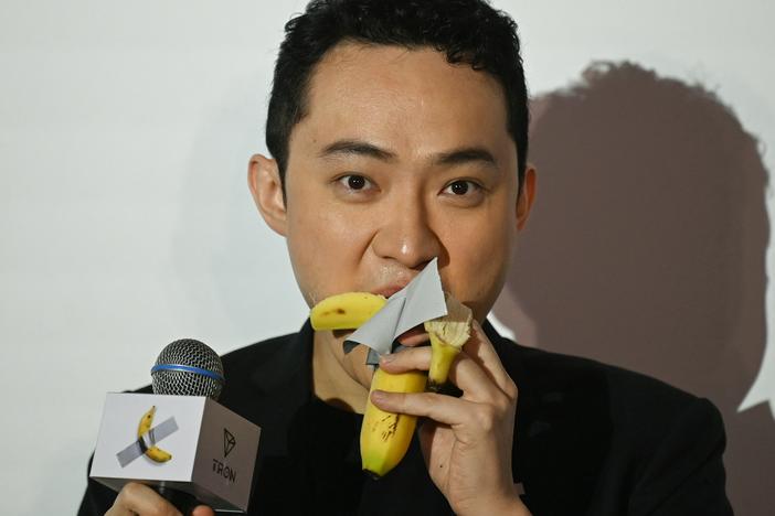 Chinese-born crypto founder Justin Sun eats a banana artwork composed of a fresh banana stuck to a wall with duct tape in Hong Kong on Friday after buying the provocative work of conceptual art by Italian artist Maurizio Cattelan at a New York auction for $6.2 million.