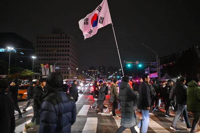 A man holds the South Korea flag outside the National Assembly in Seoul on December 4, 2024, after President Yoon Suk Yeol declared emergency martial law.