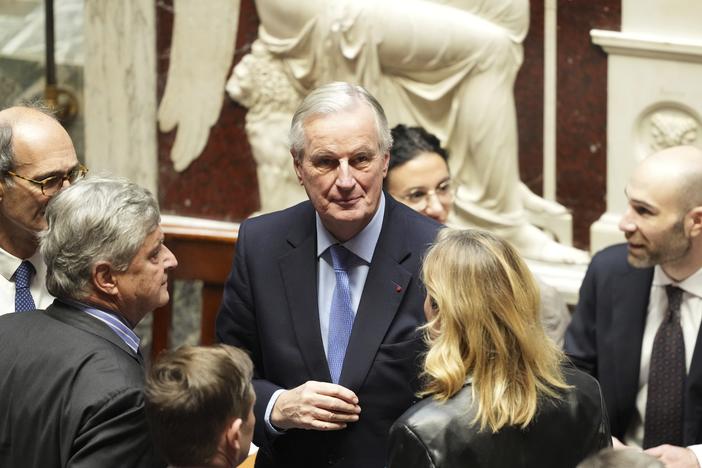 French Prime Minister Michel Barnier (center) talks to people at the National Assembly before French lawmakers vote on a no-confidence motion in Paris Wednesday.