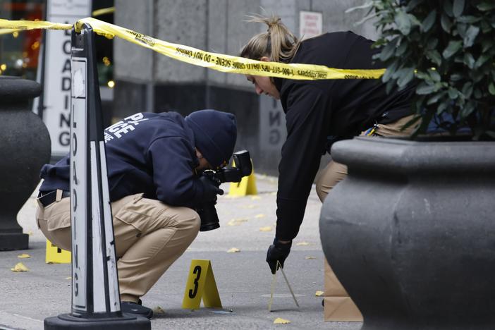 Members of the New York police crime scene unit photograph bullets lying on the sidewalk as they investigate the scene outside the Hilton Hotel in midtown Manhattan where Brian Thompson was fatally shot on Wednesday.