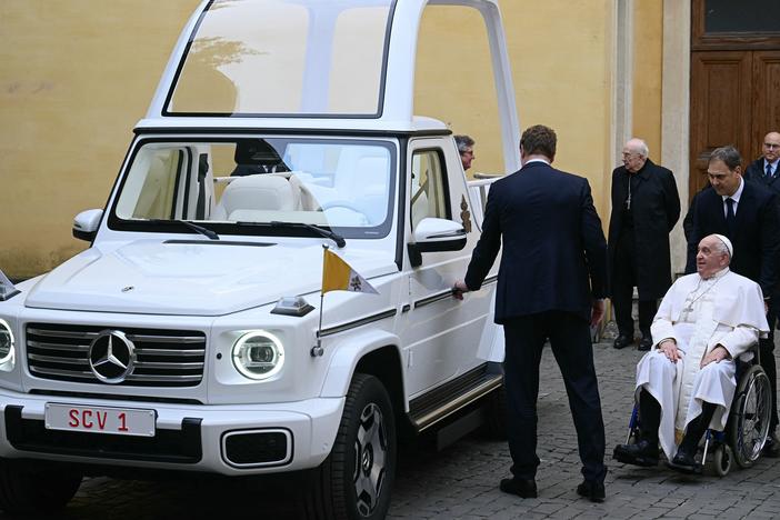 Pope Francis (right) looks on as he's presented a new fully electric popemobile at the Vatican on Wednesday.