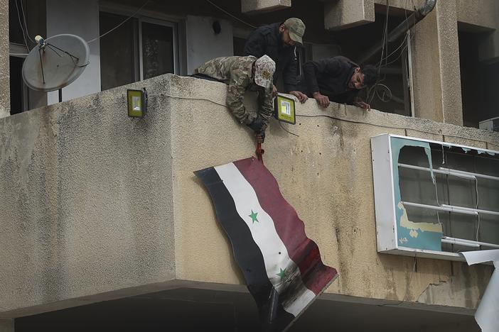 Syrian opposition fighters remove a government Syrian flag from an official building in Salamiyah, east of Hama, Syria, on Saturday.