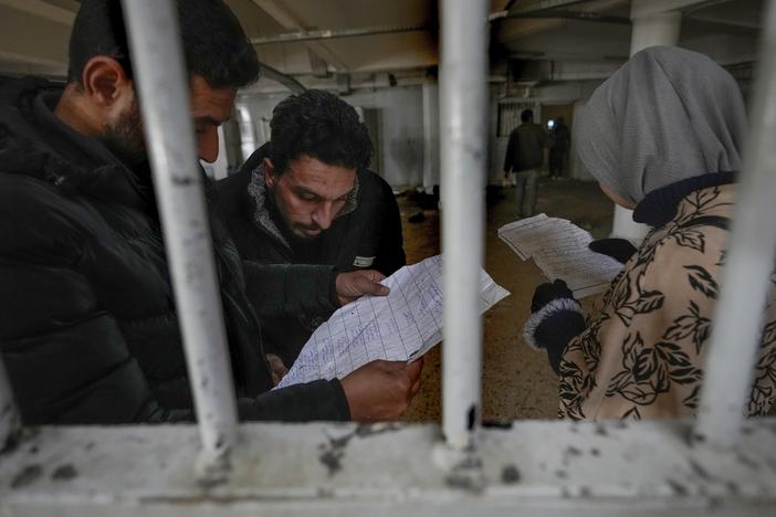 Syrians inspect documents in the infamous Saydnaya prison, just north of Damascus, on Monday. Crowds are entering the prison, known as the "human slaughterhouse," following the ouster of Bashar al-Assad and the release of thousands of prisoners who were held by the regime.