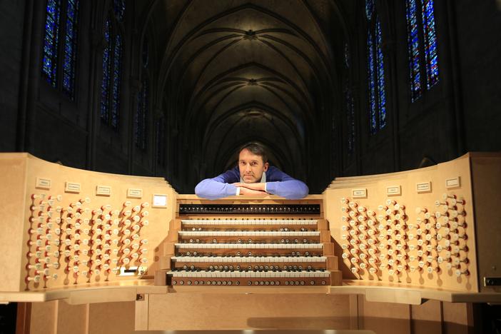 Olivier Latry, Notre Dame's longest-serving organist, poses beside the refurbished instrument, ready for the reopening ceremonies after the destructive fire in 2019.