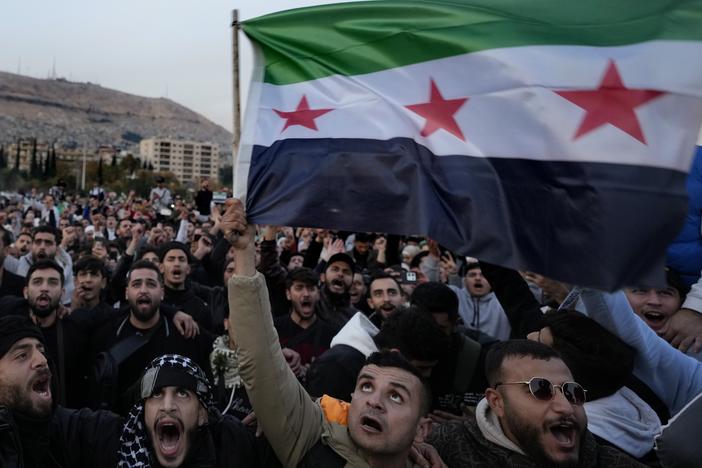 Syrian citizens wave the revolutionary flag and shout slogans, as they celebrate during the second day of the take over of the city by the insurgents in Damascus on Monday.