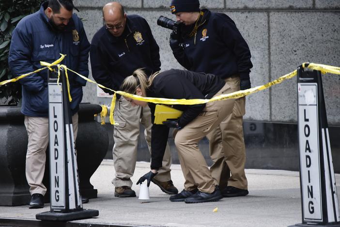 Members of the New York police crime scene unit pick up cups marking the spots where bullets lie as they investigate the scene outside the Hilton Hotel in midtown Manhattan where UnitedHealthcare CEO Brian Thompson was fatally shot on Dec. 4.